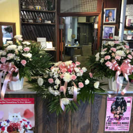 Three pink and white floral arrangements with ribbons in white containers