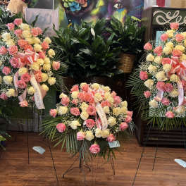 Three standing rose wreaths with pink and cream blooms and ribbons