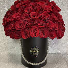 Large bouquet of red roses in a black hatbox with pearl trim