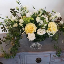 Cream and white floral arrangement in a clear pedestal vase