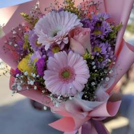 Pink and purple bouquet with gerbera daisies and a rose in pink wrap