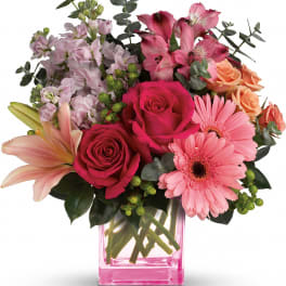 Pink and peach mixed bouquet in a pink glass vase