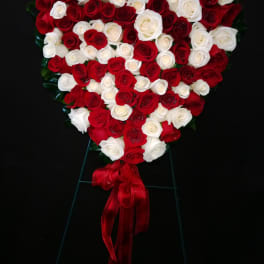 Heart-shaped arrangement of red and white roses with a red ribbon
