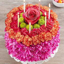 Round floral cake with candles and a pink rose center