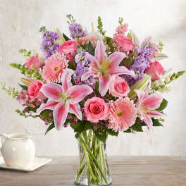 Pink lilies, roses, and daisies in a clear glass vase