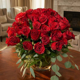 Bouquet of red roses in a glass vase with trailing greenery