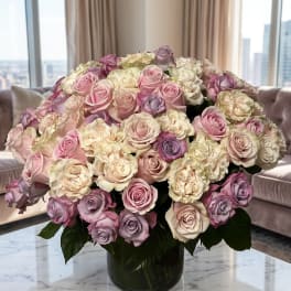 Large bouquet of pink, cream, and lavender roses in a glass vase