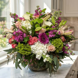 Mixed bouquet of pink, white, and green flowers in a glass bowl vase