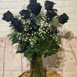 Bouquet of black roses with baby's breath in a glass vase