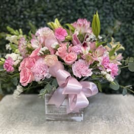 Pink bouquet of roses, carnations, and lilies in a box with a ribbon