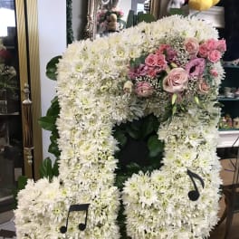 Large white floral standing arrangement with pink roses and music note accents