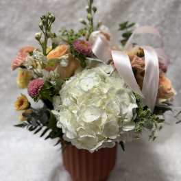 Bouquet of white hydrangea, peach roses, and pink flowers in a ribbed vase
