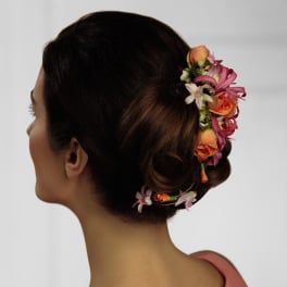 Woman wearing a floral hairpiece with pink and orange flowers