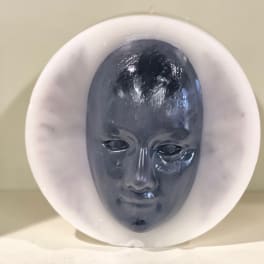 Dark sculpted face inside a white circular frame