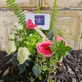 Pink and white roses arranged in a small vase with a Libra card