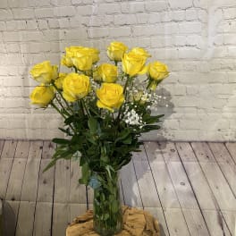 Yellow roses in a clear glass vase with white filler flowers