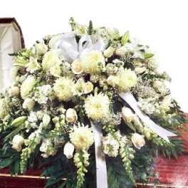 Large white funeral spray with lilies and ribbon on a stand