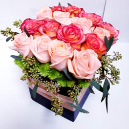 Pink and coral roses arranged in a square gift box
