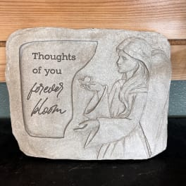 Stone plaque with a woman and the words "Thoughts of you forever bloom"