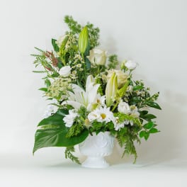 White floral arrangement in a white pedestal vase