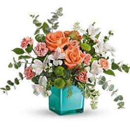 Peach roses and pink carnations in a turquoise glass vase