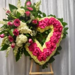 Heart-shaped floral wreath on an easel with pink and white flowers