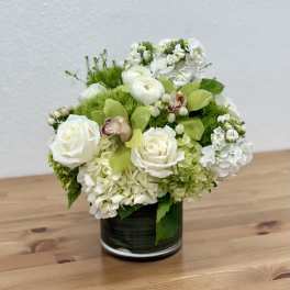 White roses and green hydrangeas arranged in a dark glass vase