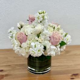 Pink roses and white flowers arranged in a glass vase