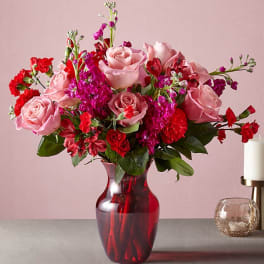 Pink roses and red carnations in a red glass vase
