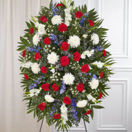 Standing funeral spray with red roses, white mums, and blue flowers