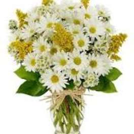 Bouquet of white daisies and yellow flowers in a clear glass vase