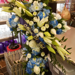 Large blue and white funeral spray with lilies and roses on a stand