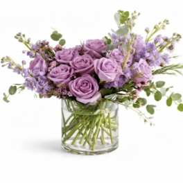 Lavender roses and purple flowers in a clear glass vase