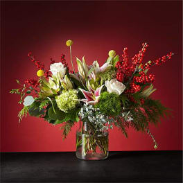 Mixed floral arrangement in a clear glass vase with red berry branches