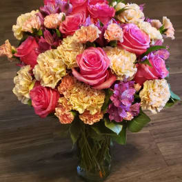 Bouquet of pink roses and peach carnations in a glass vase