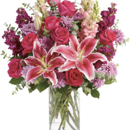 Pink roses and lilies arranged in a clear glass vase