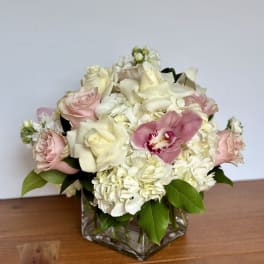 Pink and white roses with hydrangeas in a square glass vase