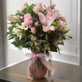 Pink and white mixed flower bouquet in a pink vase with ribbon