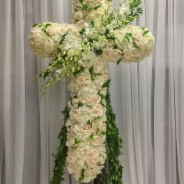 Large floral cross made of white and cream roses with trailing greenery