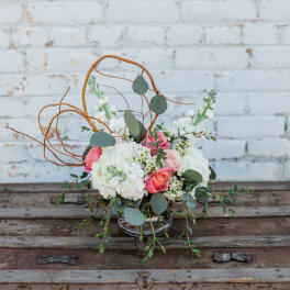 Pink and white floral arrangement in a glass vase with curly branches
