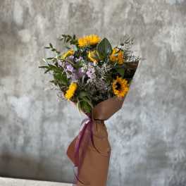 Bouquet of yellow sunflowers and lavender flowers wrapped in brown paper