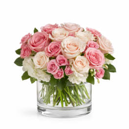 Pink and cream roses arranged in a clear glass vase