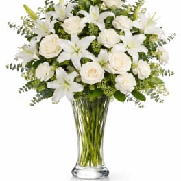 White lilies, roses, and carnations in a clear glass vase
