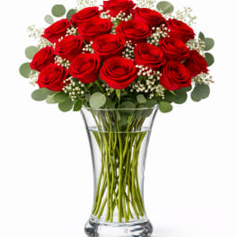 Red roses arranged in a clear glass vase with baby's breath