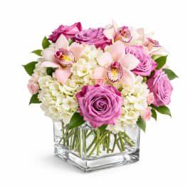 Pink roses and pale orchids in a clear square vase