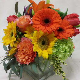 Bright mixed bouquet with sunflowers, gerbera daisies, roses, and hydrangea in a glass vase