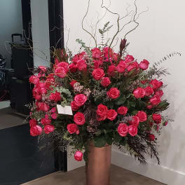 Large arrangement of pink roses in a tall copper vase