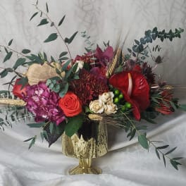 Mixed floral arrangement in a gold vase with red and pink blooms