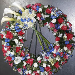 Circular floral wreath with white calla lilies and red, blue, and white blooms