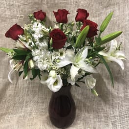 Red roses and white lilies arranged in a dark vase